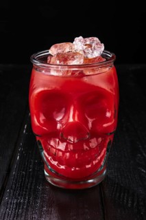 Cocktail bloody Mary in skull cup on dark wooden background