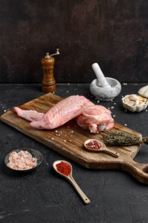 Raw turkey wing on wooden cutting board