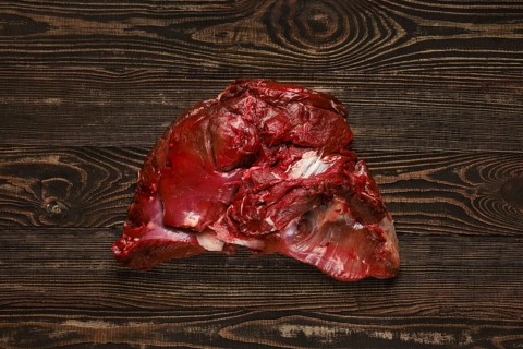 Overhead view of raw deer boneless ham over wooden background