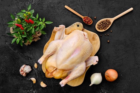 Fresh raw whole farm chicken on wooden cutting board