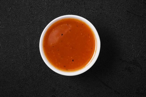 Overhead view of small bowl with spicy orange sauce for poultry