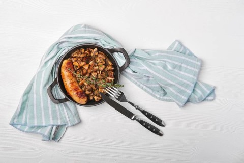 Cast-iron pan with fried sausage and mushrooms