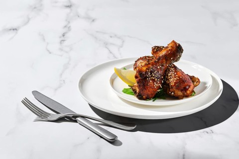 Portion of baked chicken legs with spicy sauce on a plate