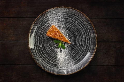 Top view of plate with piece of peanut cake on wooden background