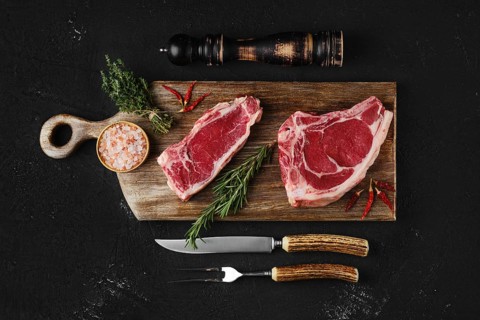 Raw strip steak bone in and boneless on dark background