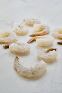 Peeled fresh raw white prawns on wooden background