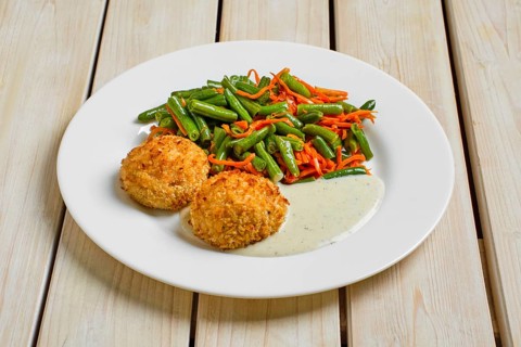 Meatballs in breading served with green bean and spicy carrot on wooden table