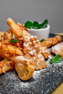 Close up view of deep fried fruits in breading served with caramel and strawberry jam