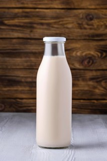 Bottle of soy milk on white table over dark wooden background