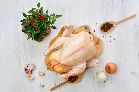 Fresh raw whole farm chicken on wooden cutting board