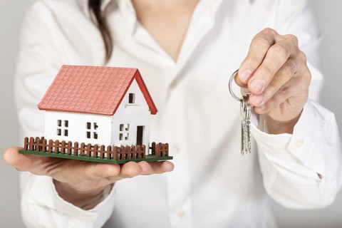 Female holding a toy model house and keys