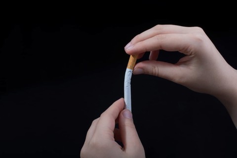 Hand is breaking a cigarette on a black background