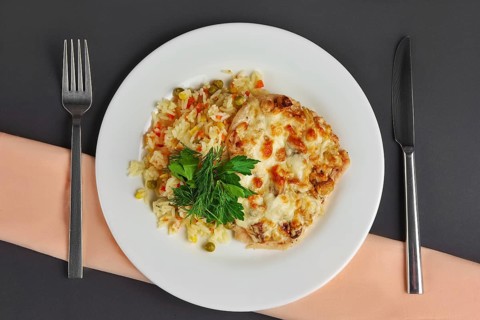 Top view of chicken fillet with mushrooms and cheese garnished with rice