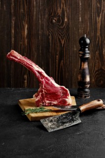Raw prime ribeye steak on wooden cutting board