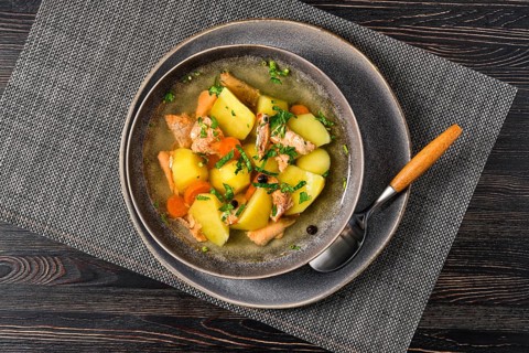 Top view of red salmon fish soup with potato and carrot