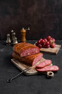 Homemade smoked beef sausage in organic casing on wooden cutting board