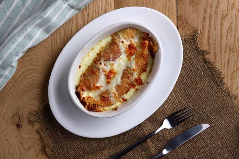 Top view of fried pancakes stuffed with ham and covered with melted cheese on wooden table