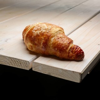 Fresh crisp croissant with powdered sugar on the corner of wooden table