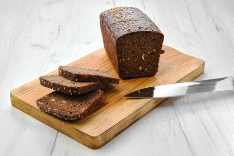 Top view of loaf of brown sourdough bread with sunflower seeds and sesame
