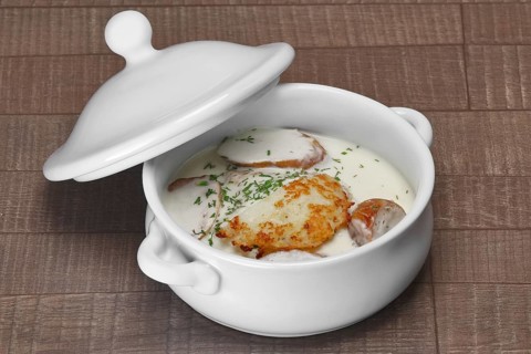 White bowl with machanka and potato pancakes on wooden table