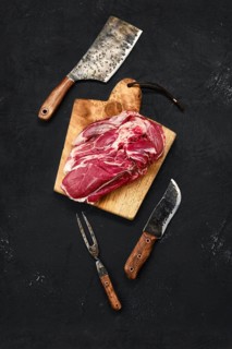 Overhead view of raw lamb shoulder without bone on wooden cutting board