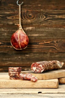 Smoked dried pork sausage cut on slices on wooden cutting board