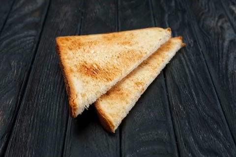 Two pieces of toast bread on dark wooden table. Top view