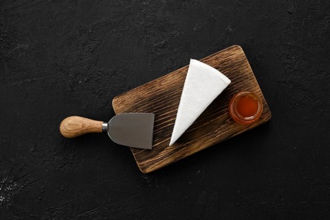 Piece of soft brie or camembert cheese on cutting board