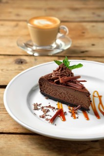 Piece of chocolate cake with cappuccino on wooden table