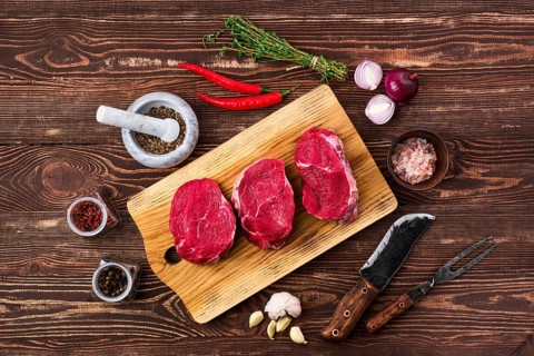Overhead view of marinated beef fillet mignon with spice on wooden table