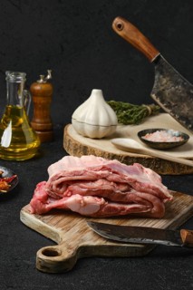 Raw veal ribs with ingredients for cooking on black background