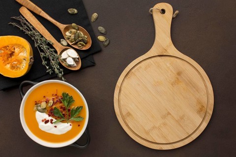 Flat lay of winter squash soup in bowl with chopping board and spoons