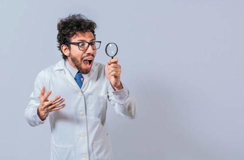 Surprised scientist observing with a magnifying glass to the side. Scientist holding a magnifying glass looking to the side