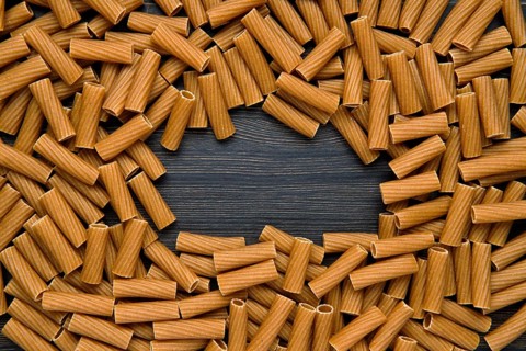 Top view of tortiglioni pasta with copy space place. Grooved helical tube pasta