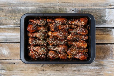Overhead view of baked chicken legs with spicy sauce on a baking tray