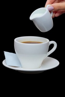 Pouring milk in coffee. Photo with clipping path isolated on black background