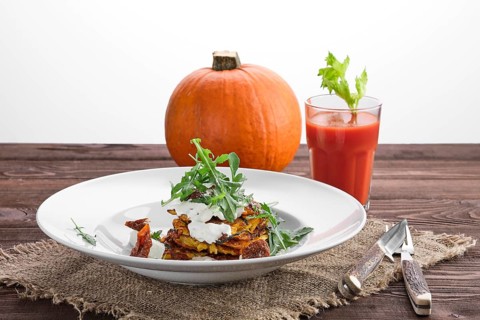 Pumpkin fritters with sour cream with whole pumpkin and tomato juice on background