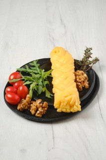 Smoked braided cheese with walnuts and tomatoes on a plate