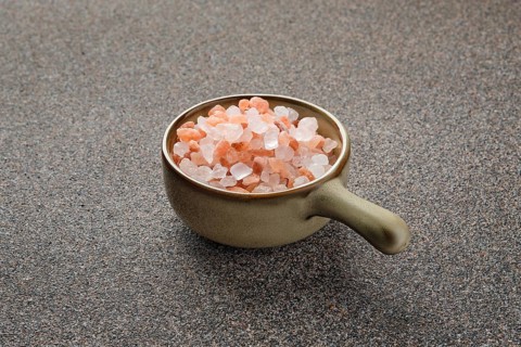 Pink Himalayan salt in a ceramic bowl on stone background