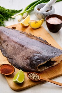 Raw fresh halibut without head on wooden cutting board