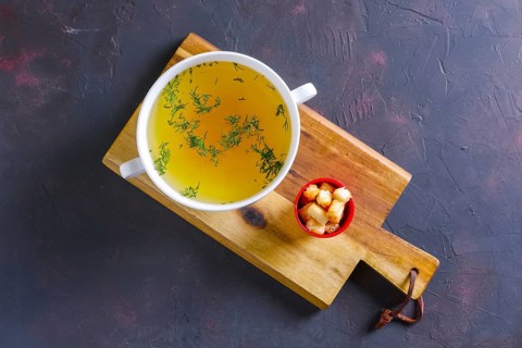 Plate with clear soup and pieces of white bread crouton