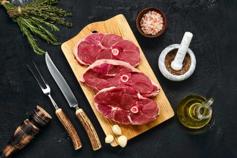 Overhead view of three lamb steak swith spice and knife and fork with horn handle