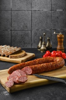 Smoked beef sausage rings on wooden cutting board on kitchen table