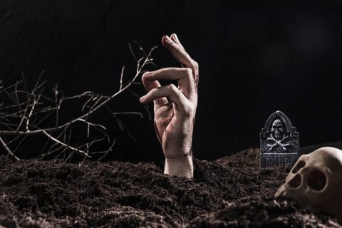 Hand sticking out ground near skull
