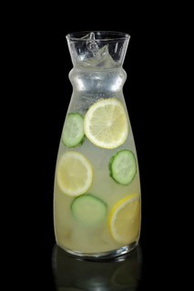 Decanter with lemon and cucumber lemonade isolated on black