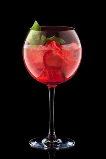 Big round wine glass with fresh cold lemonade isolated on black background