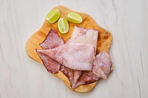 Top view of raw fresh unpeeled squid on wooden cutting board