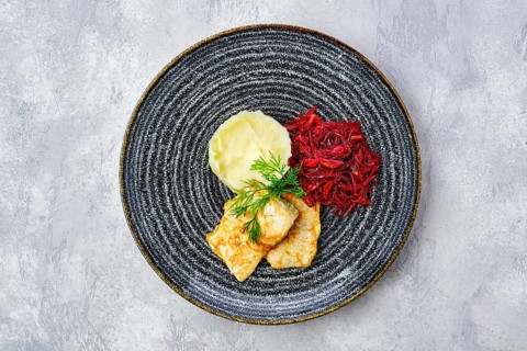 Top view of fried hake in breading with mashed potato and roasted beetroot