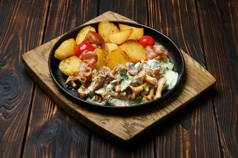 Potato wedges with chanterelles and pork in cast iron skillet