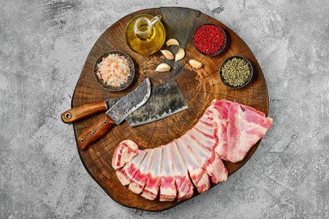 Raw fresh lamb flap ribs with ingredients on wooden log
